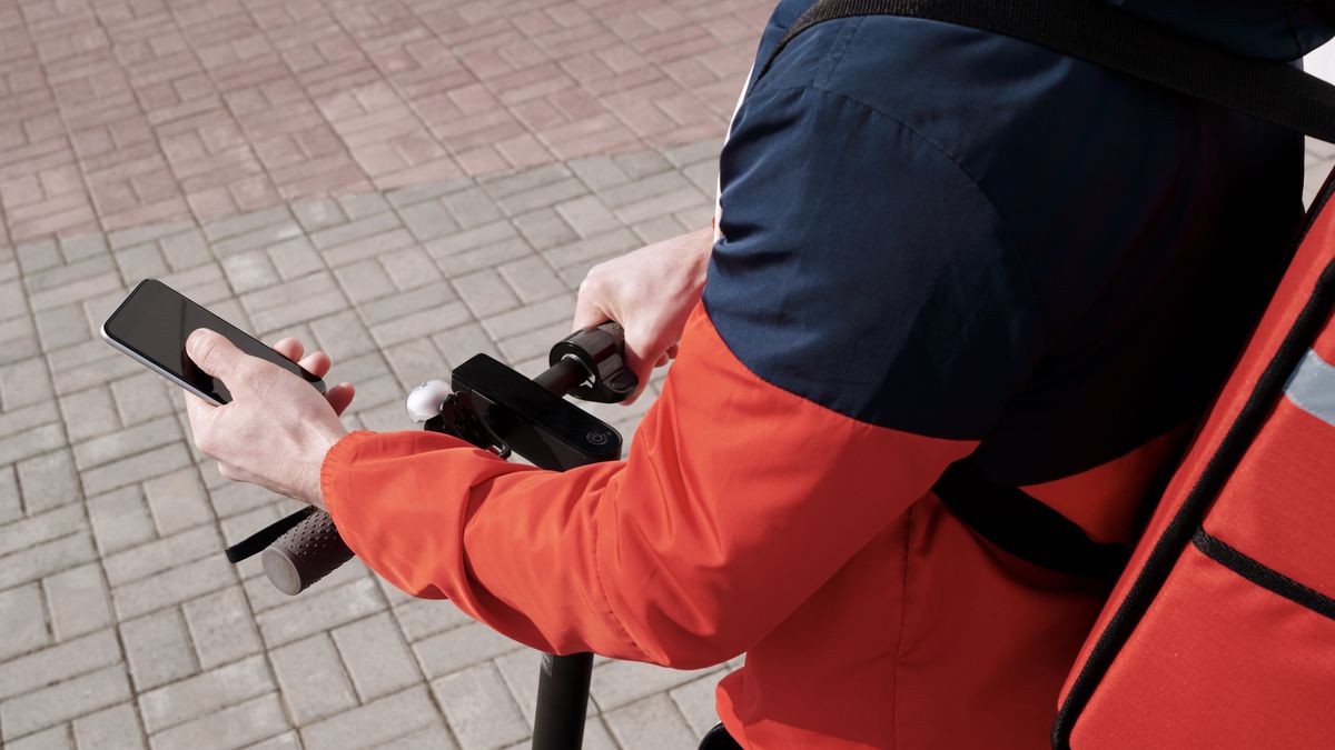Delivery rider using smartphone navigation on an electric scooter