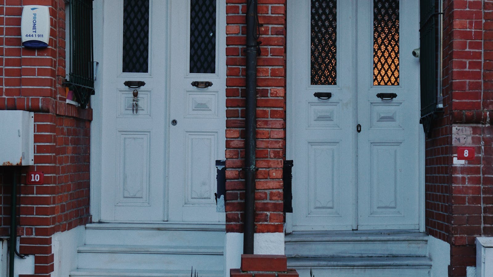 Symmetrical red brick duplex rental property with paired white front doors