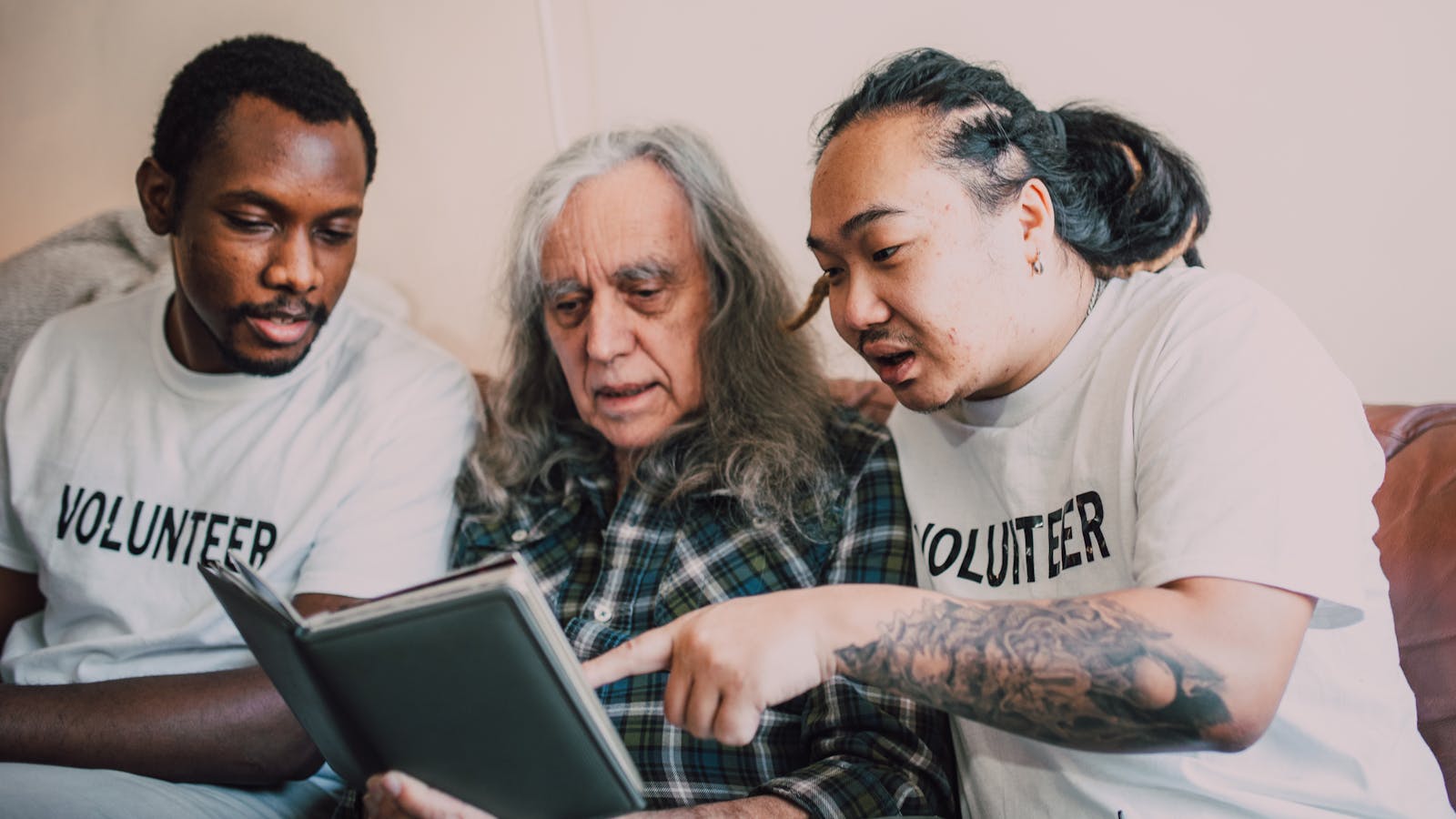 Volunteers helping an elderly community member with a photo album