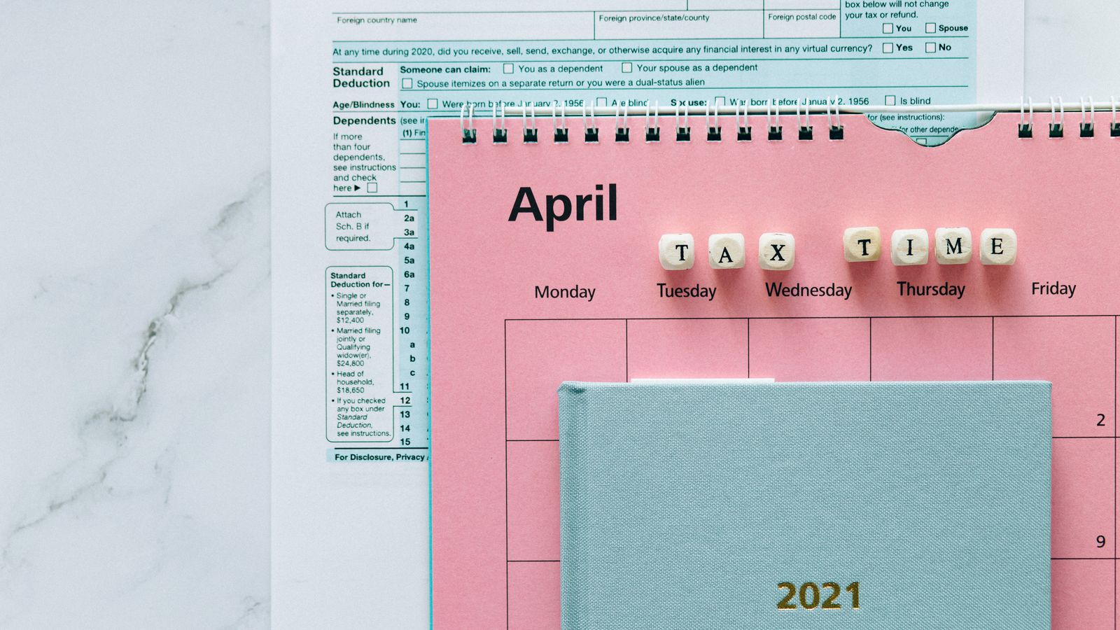 April tax deadline calendar with federal tax forms on a desk